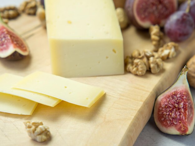 Нарезка сыра с фруктами - орехами и инжиром на деревянной доске. Вкусная закуска