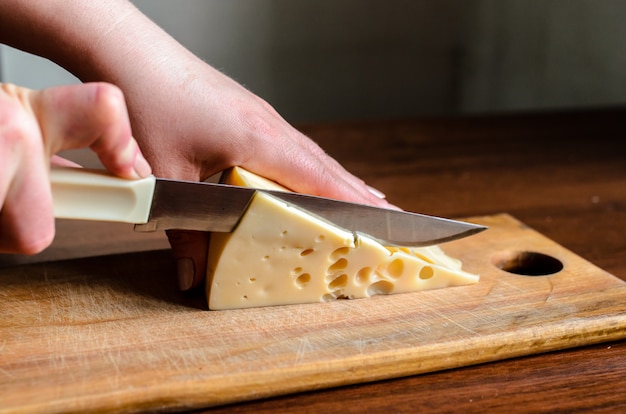 Slicing cheese on a wooden board.