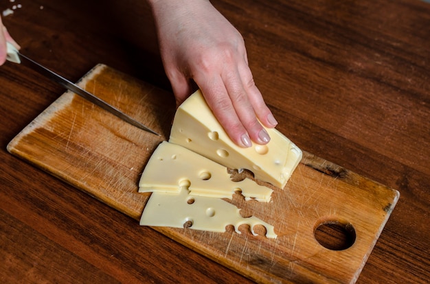 Affettare il formaggio su una tavola di legno.