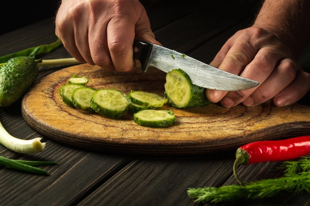 まな板の上できゅうりをスライスする新鮮な野菜と朝食のためのおいしいサラダ