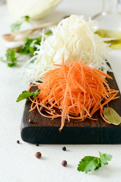 Slicing Fresh cabbage and carrots on a wooden board on a light background. Vegetables for ferment, for long fermentation. Assortment of fresh vegetables. Healthy food conception.