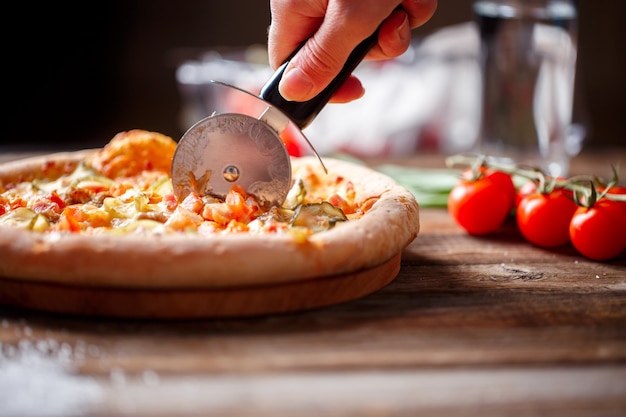 Slicing fresh pizza with roller knife