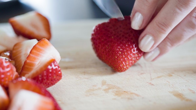 Slicing fresh strawberries on a wood cutting board.