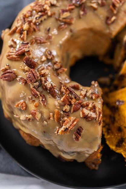 Slicing homemade chocolate pumpkin bundt cake with toffee glaze.