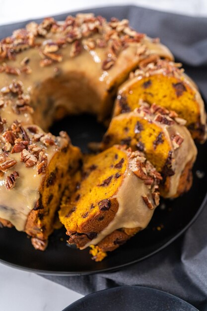 slicing homemade chocolate pumpkin bundt cake with toffee glaze