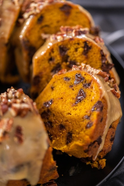 Slicing homemade chocolate pumpkin bundt cake with toffee glaze