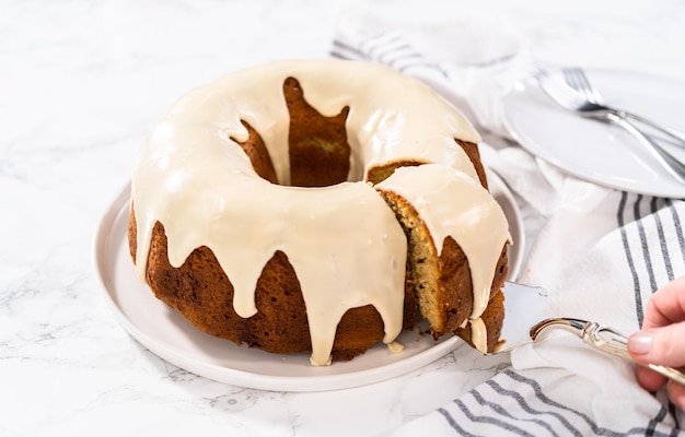 Photo slicing homemade eggnog bundt cake with an eggnog glaze