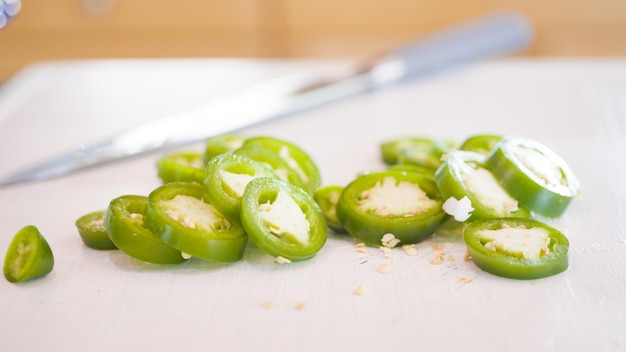 Slicing jalapeno peppers on a wood cutting board.