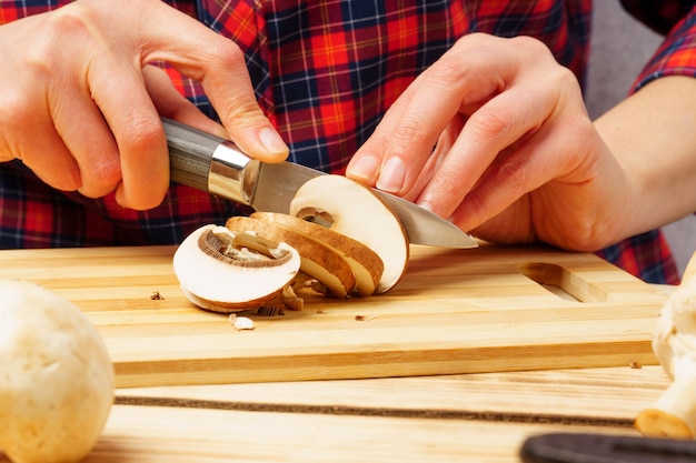 Slicing mushrooms. close-up of female hands slicing champignons on a cutting board.