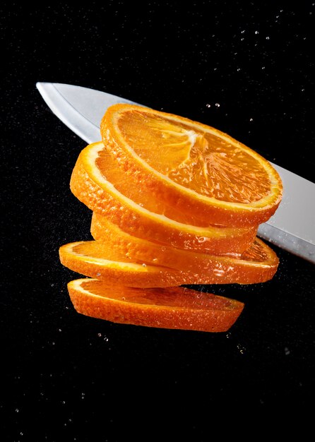 Slicing an orange with a knife on a black background