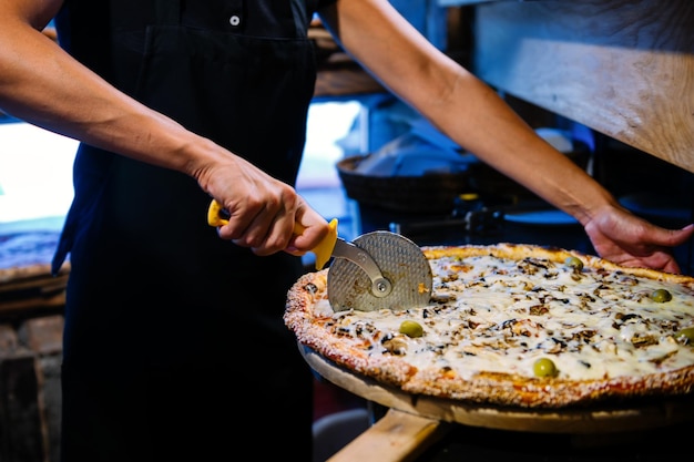 Foto affettare la pizza con il mattarello sulla buccia di legno