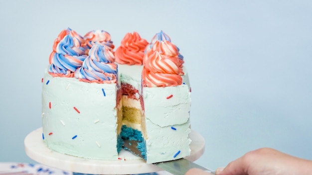 Slicing red, white, and blue three-layer cake.