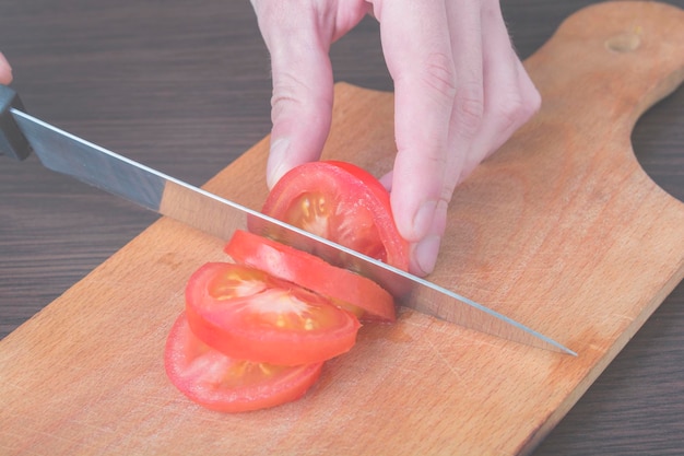 Slicing a tomato with a knife on a board