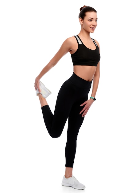 Slim athletic caucasian woman in sport wear doing stretching exercise in white isolated background