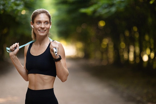 Slim athletic woman having workout outdoors holding skipping rope