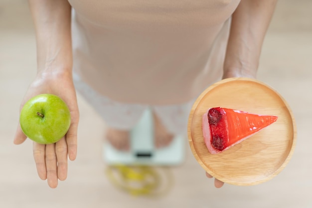 날씬한 몸매 여성은 건강한 음식과 정크푸드 중에 선택합니다 여성은 다이어트를 위해 녹색 사과를 선택합니다 건강에 좋은 음식 체중 감량 균형 조절 지방 감소 저칼로리 루틴 운동