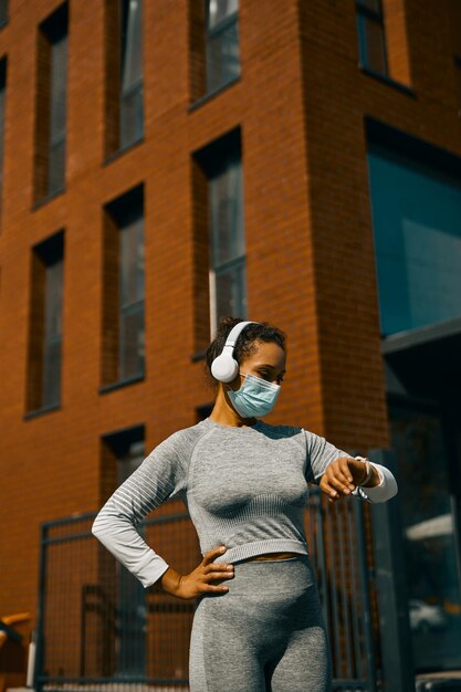 Slim fit woman looking at her results on smart watch while standing outdoors