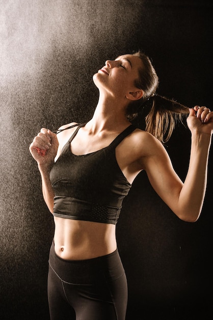 Slim fitness woman in black sport suit posing on black background