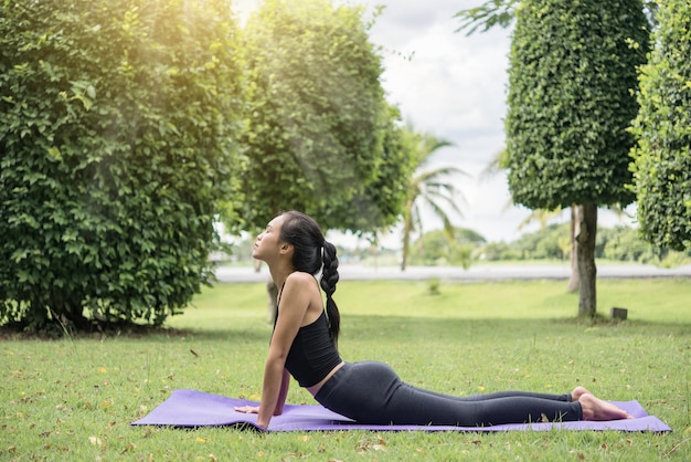 Slim girl play yoga on the lawn at the parkrelax in nutureAsian Girls love health practicing yoga