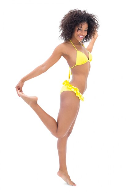 Slim girl in yellow bikini smiling at camera