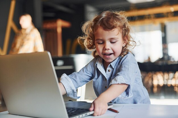 Slim kind in vrijetijdskleding die laptop gebruikt voor onderwijsdoeleinden of plezier