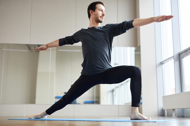 Slim man doing standing yoga pose