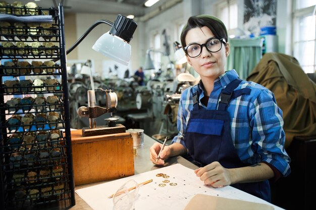 Slim meisje aan het werk bij de montagewinkel van de horlogefabriek