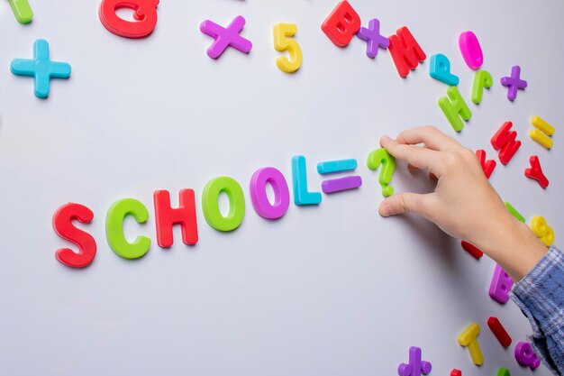 Foto slim schoolkind dat bij het bord staat en kleurrijke letters vasthoudt