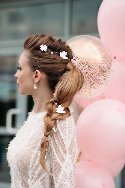 Slim splendida bruna con fiori tra i capelli e abito bianco.