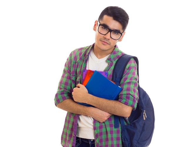 Slim uitziende jonge man in wit T-shirt en geruit hemd met blauwe rugzak met boeken