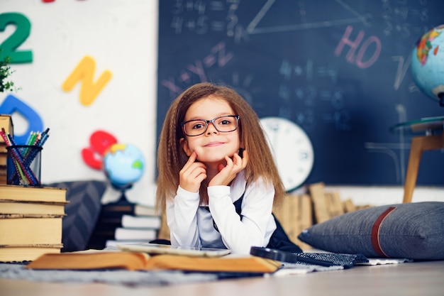 Slim weinig schoolmeisje met digitale tablet in een klaslokaal.