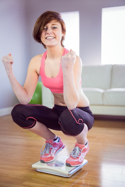 Slim woman cheering on scales