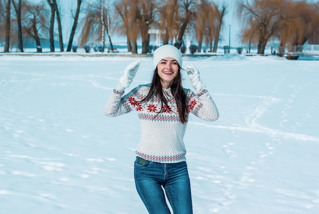 Slim woman in jeans and a sweater laughs Hands near face White