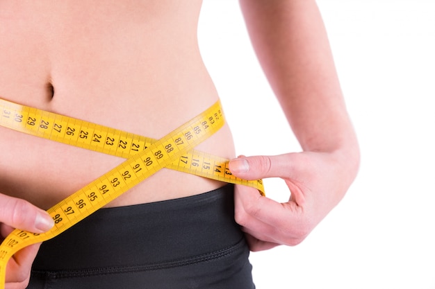 Slim woman measuring waist with tape measure