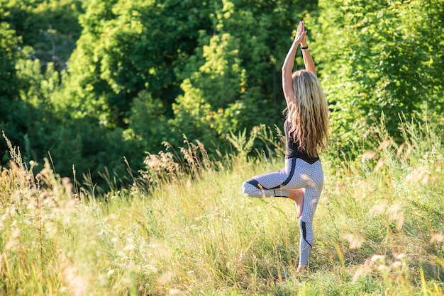 Slim woman practices yoga in nature on a sunny day