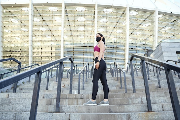 Slim woman in protective face mask standing on the steps