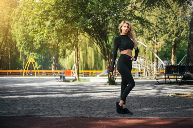 Slim woman standing and showing body outside green park morning looking at the camera