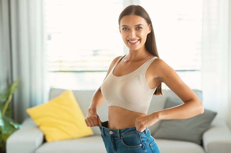 Photo 室内で減量した後、古い特大のジーンズを着ているスリムな女性