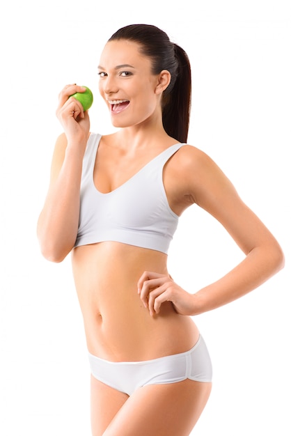 Slim woman in white underwear with green apple at her hands over isolated background