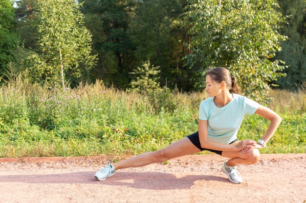 Slim young girl stretching her legs outdoors