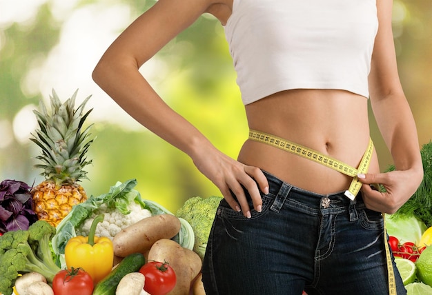 Slim young woman measuring her thin waist with a tape measure, close up