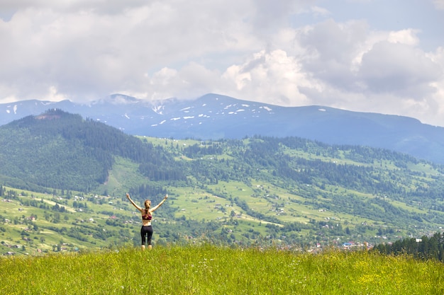 Slim young woman with raised arms outdoors