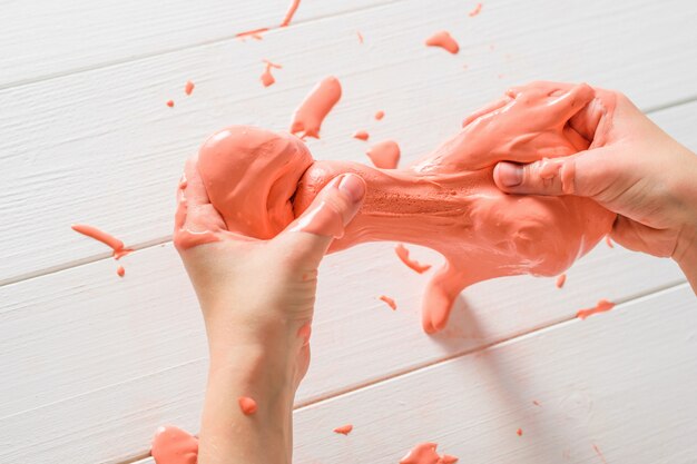 Slime is stretched and drops on white table.