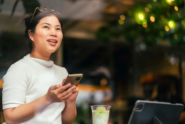 Slimme aantrekkelijke positieve Aziatische digitale nomade vrouw met casual doek werk op afstand nieuwe normale levensstijl handgebruik tablet teleconferentie onlive videogesprek vergadering op afstand in coffeeshop café