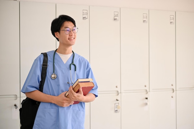 Slimme Aziatische mannelijke medische student in een uniform staat in een kleedkamer