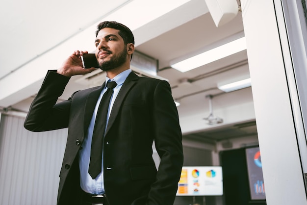 Slimme en positieve zakenman die alleen op kantoor belt en praat op een smartphone Professioneel zakelijk bellen aan de telefoon en binnenshuis genieten van zakelijke mobiele gesprekken