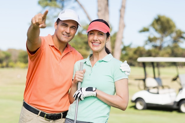 Foto slimme golfspelerman die terwijl status door vrouw richt