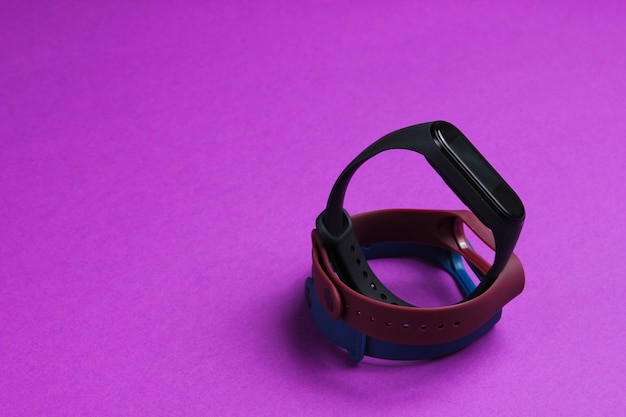 Slimme horloge met verwisselbare armbanden op paarse achtergrond. Fitnesstracker. Moderne gadgets