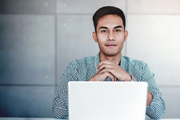 Slimme jonge Aziatische zakenman die aan Computerlaptop in Bureau werkt. Lachend en kijkend naar Camera