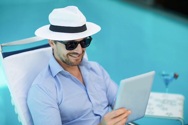 Slimme man met behulp van digitale tablet in de buurt van zwembad